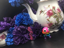 Load image into Gallery viewer, image is a magenta tentacle earring with black paint engraving. background of image has blue and purple silk flowers (carnations) and a white floral-patterned teapot and teacup. next to the earring is a small rainbow penis with googly eyes.