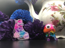 Load image into Gallery viewer, image is a clear heeled boot with a pink heart and laces engraved with whitee paint. there are swirls of pink, purple, and blue behind the paint engraving.  background of image has blue and purple silk flowers (carnations) and a white floral-patterned teapot and teacup. next to the earring is a small rainbow penis with googly eyes. 
