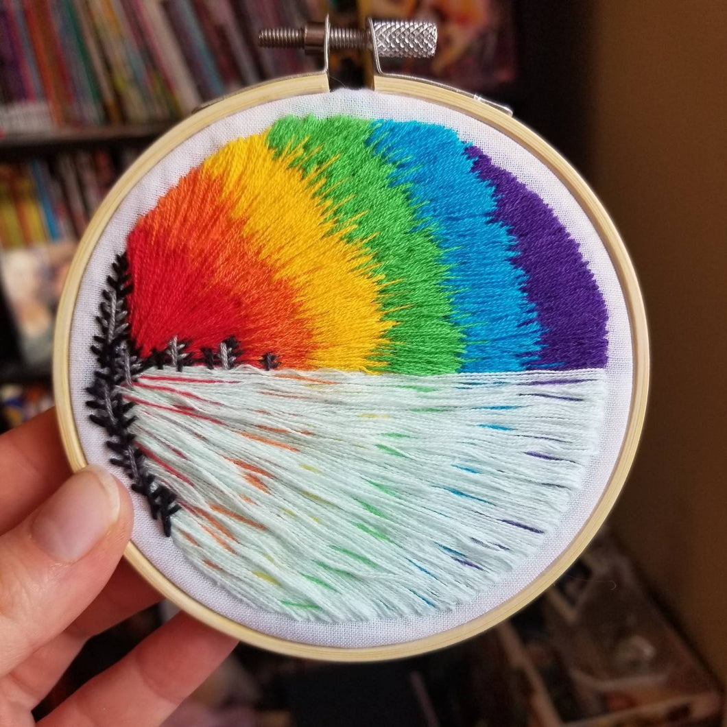 Dont be afraid to make waves. Hand embroidered landscape art hoop with a rainbow and lake and trees for LGBTQ pride month