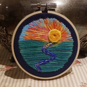 Hand embroidered modern landscape art of a sunrise or set with a river